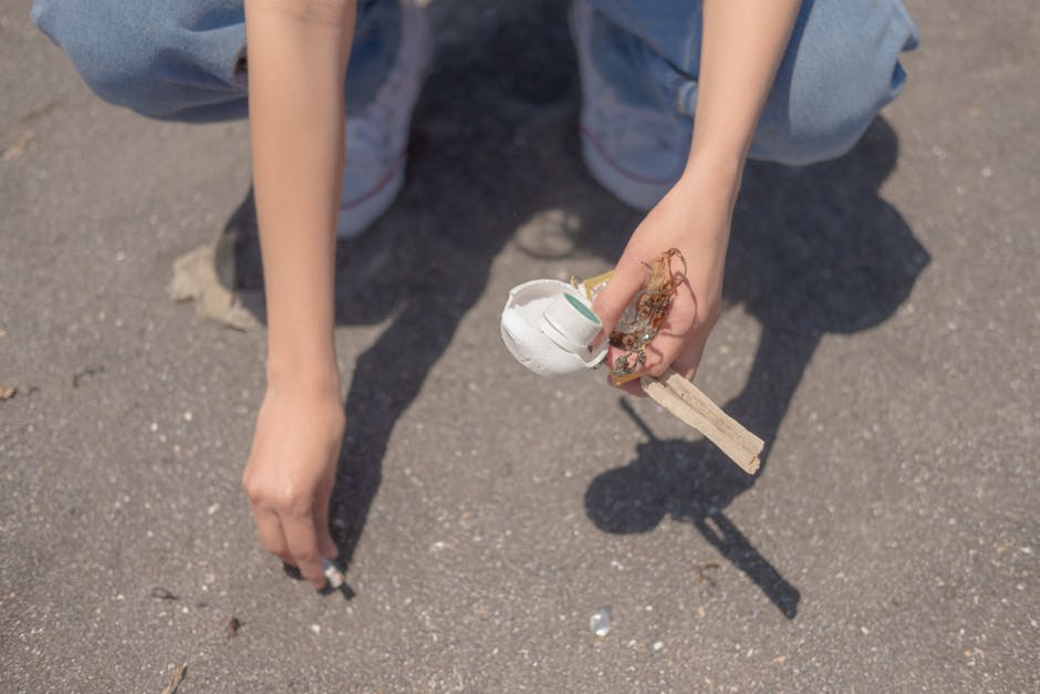 A crumpled plastic bag made from thin, glossy material with a mix of blue, white, and green colors lies discarded on the pavement next to a concrete curb. The bag appears to contain or was holding lig
